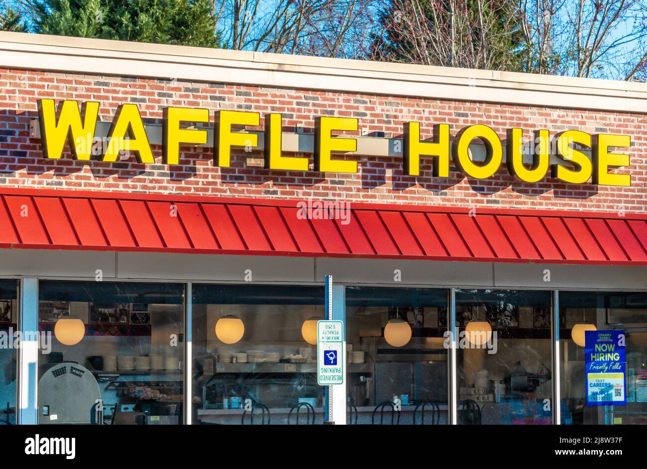 Außenwerbung, Markenwerbung und Logo für das zwanglose Restaurant „Waffle House“ in Gelb, Blockbuchstaben über roter Markise und Glasfenstern. Stockfoto
