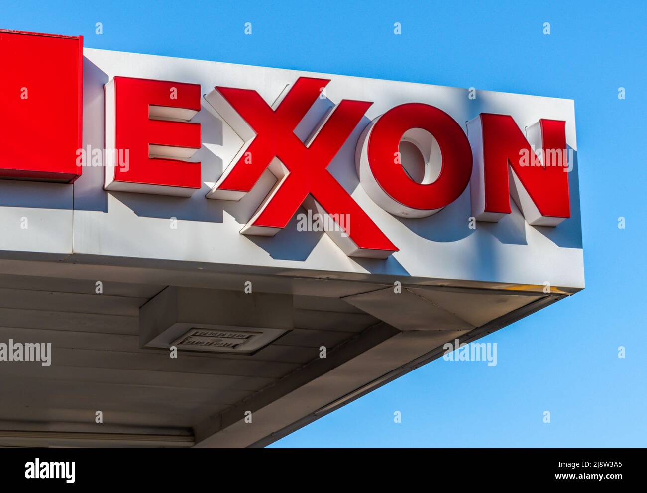Außenwerbung, Marken- und Logo-Beschilderung für „Exxon“-Benzin in Weiß mit roten Buchstaben vor einem klaren blauen Himmel bei Sonnenuntergang in Charlotte, North Carolina. Stockfoto