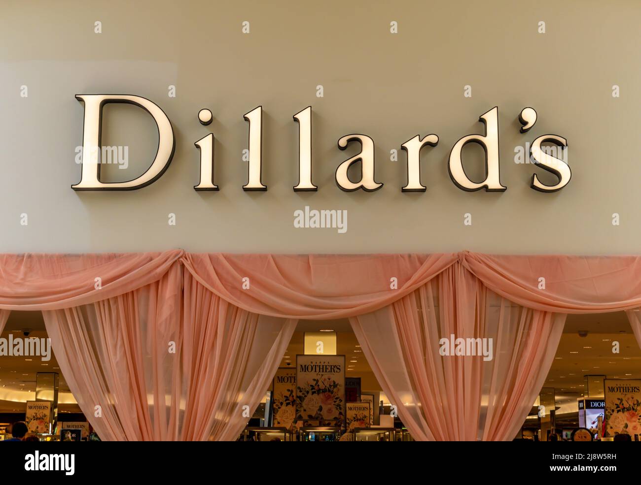 Dillards Fassade und Logo in Gold über durchsichtigen lachsfarbenen Vorhängen und Innenraumbeleuchtung. Stockfoto