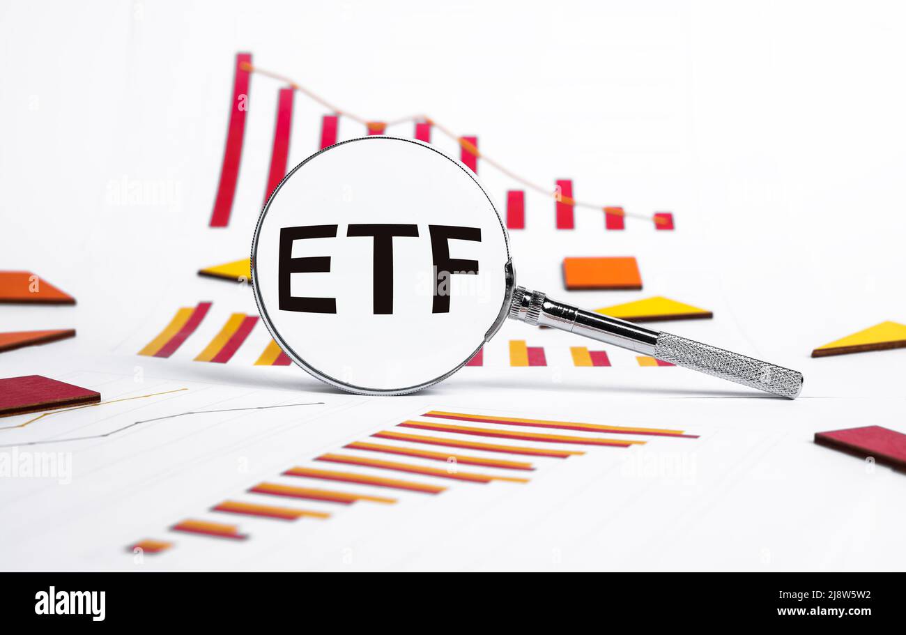 Börsengehandelter Fonds. Lupe mit ETF-Text und Grafiken, die einen Kursverfall an den Aktienmärkten zeigen. Analyse der wirtschaftlichen Rezession und Krise, Risiken durch den Kauf oder Verkauf von Aktien. Hochwertige Fotos Stockfoto