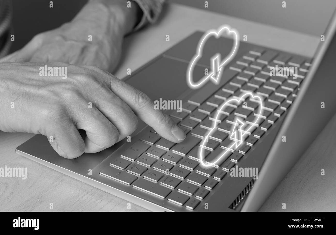 Cloud-Computing. Mann mit Laptop zum Herunterladen von Dateien aus dem Online-Speicher. Nahaufnahme des Zeigefingers durch Drücken der ENTER-Taste. Schwarz und Weiß. Hochwertige Fotos Stockfoto