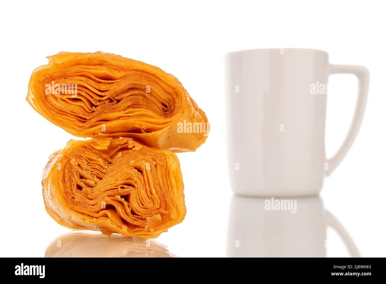 Zwei Scheiben süßer Honig-Baklava mit einer weißen Tasse, Nahaufnahme, isoliert auf weißem Hintergrund. Stockfoto