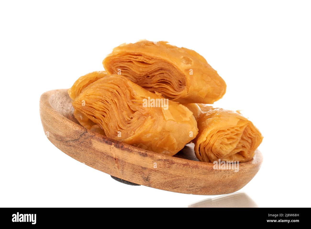 Mehrere Scheiben süßer Honig-Baklava auf einem Holztablett, Nahaufnahme, isoliert auf weißem Hintergrund. Stockfoto