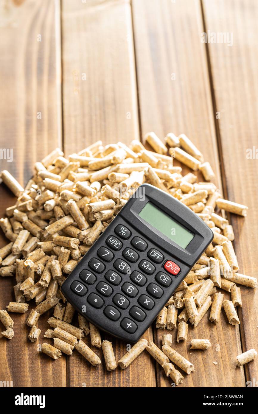Holzpellets und Rechner, Biokraftstoff auf einem Holztisch. Ökologischer Brennstoff aus Biomasse. Erneuerbare Energiequellen. Stockfoto