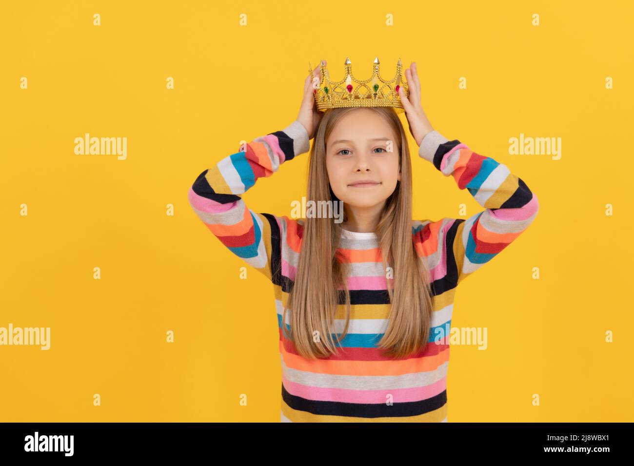 Egoistisches Teenager-Kind in Königskrone auf gelbem Hintergrund Stockfoto