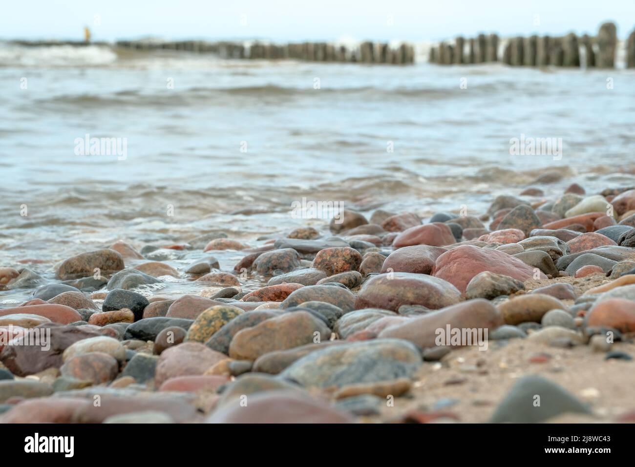 Blick auf einen Sandstrand und Felsen und im Hintergrund das blaue Mittelmeer beim bunten Sonnenuntergang. Schöner Meerblick. Bäume am Wasser. Stockfoto