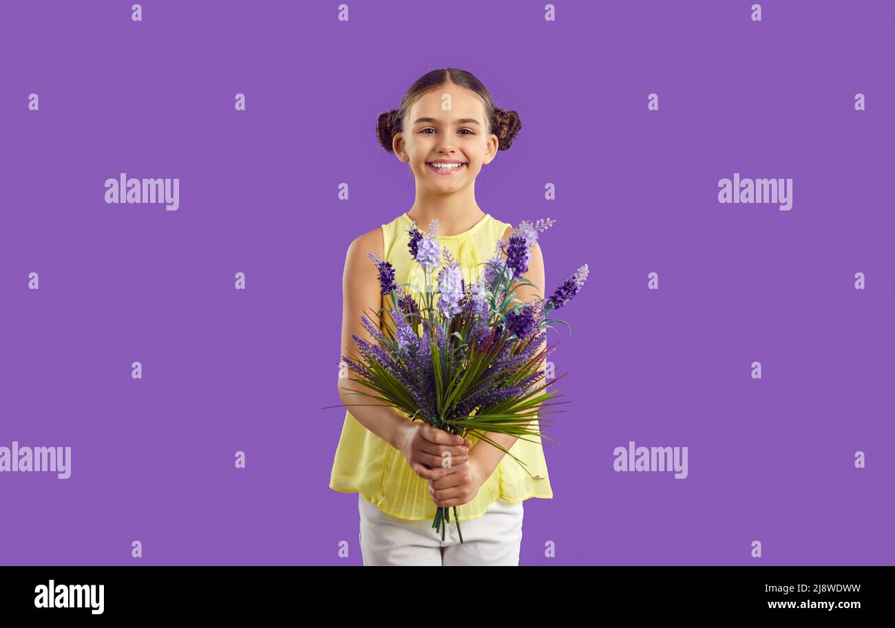 Schöne niedliche kleine präteen Mädchen mit Blumenstrauß von Lavendel auf lila Hintergrund isoliert. Stockfoto