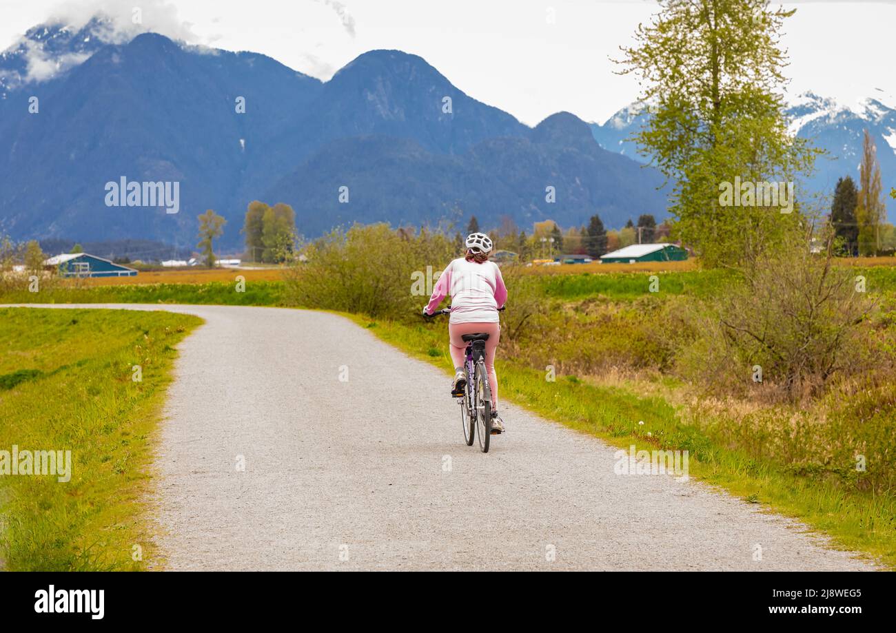 Ältere Frau, die im Sommerpark Fahrrad fährt. Aktives Alter, Menschen und Lifestyle-Konzept. Selektiver Fokus, Straßenfoto Stockfoto