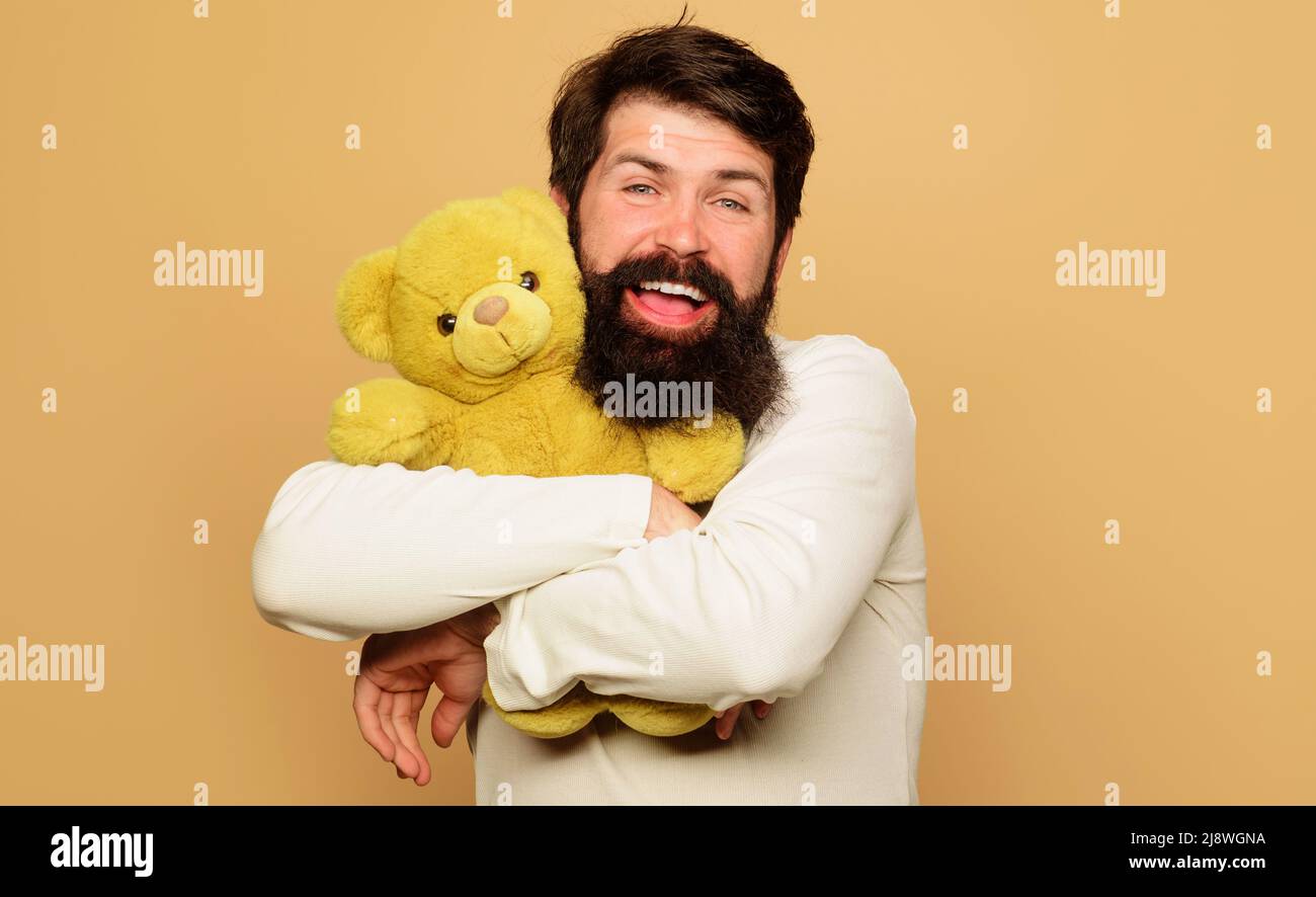 Lächelnder bärtiger Mann umarmt Teddybär. Geburtstagsfeier. Happy Guy Umarmung weichen Plüsch Spielzeug. Stockfoto