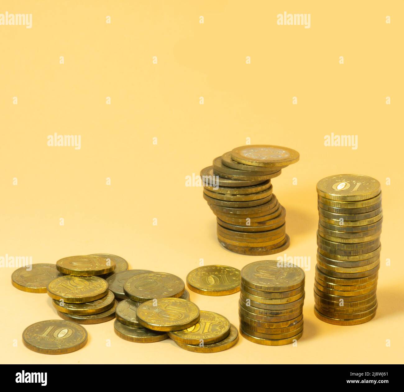 Stapel von Münzen, verstreute Kleinigkeiten. Geld auf gelbem Hintergrund Stockfoto