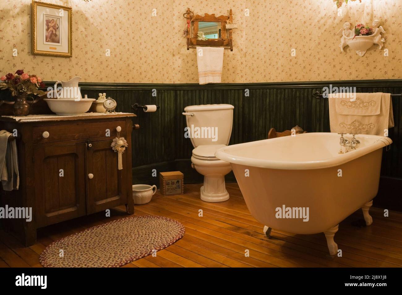 Freistehende Badewanne mit freistehender Fußspitze, Holzwaschtisch im Badezimmer im alten Steinbruch-Haus aus dem Jahr 1831 von Canadiana. Stockfoto