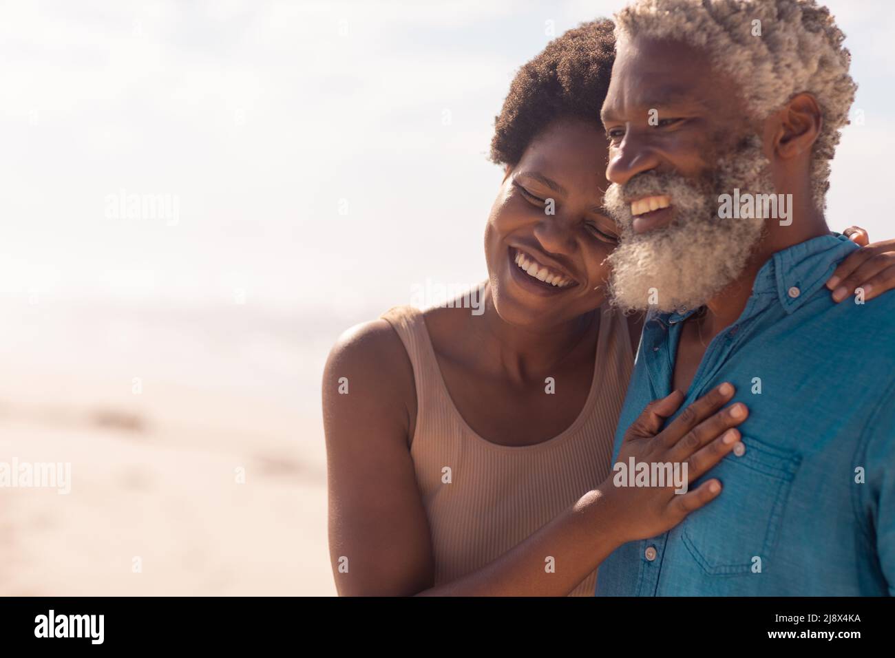 Fröhlicher bärtiger afroamerikanischer Seniorchef und reife Frau mit afro-Haaren genießen am Strand Stockfoto