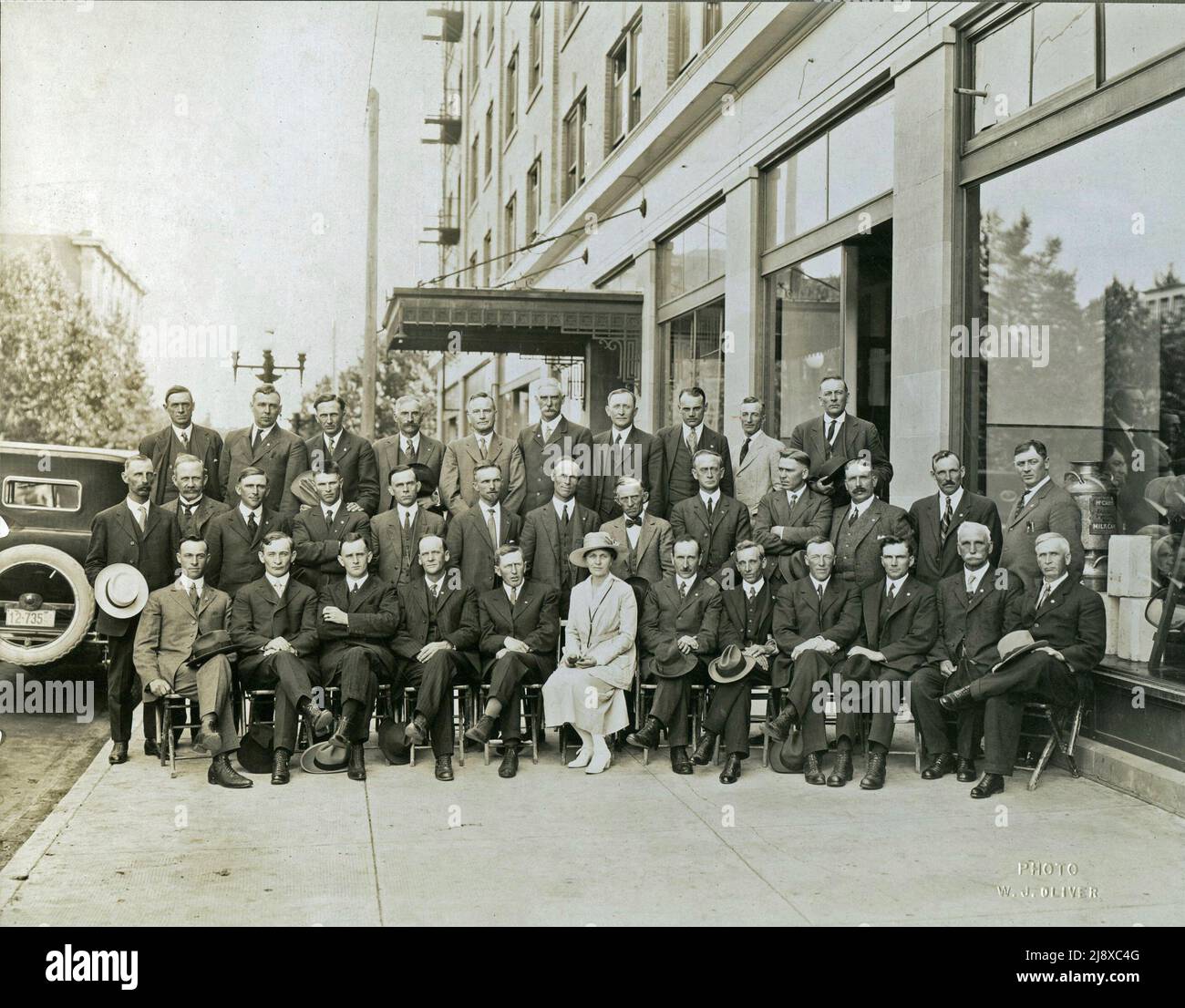 S/W-Foto der gesetzgebenden UFA-Mitglieder von Alberta, die am 1921. Juli vor dem Lougheed-Gebäude gewählt wurden. Die Bildunterschrift lautet: Front Row (von links nach rechts) - G. A. Forster, Lorne Proudfoot, A. M. Matheson, L. Peterson, N. S. Smith, Frau W. Parlby, Geo. MacLachlan, S. A. Carson, D. M. Kennedy, E. C. Cook, G. W. Smith, W. C. Smith / Middle Row (von links nach rechts) - W. M Washburn, Geo. Hoadley, G. N. Johnson, Laudas Joly, W. Fedun, D. H. Galbraith, Alex Moore, M. J. Conner, C. O. F. Wright, O. L. McPherson, D. Cameron, W. H. Shield, A. B. Claypool / Back Row (von links nach rechts) - P. J. Enzenauerm Stockfoto