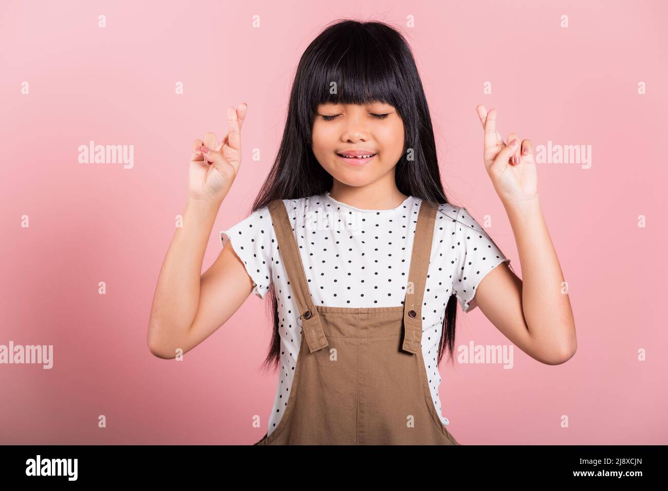 Asiatische kleine Kind 10 Jahre alt lächeln über die Finger und geschlossenen Augen im Studio