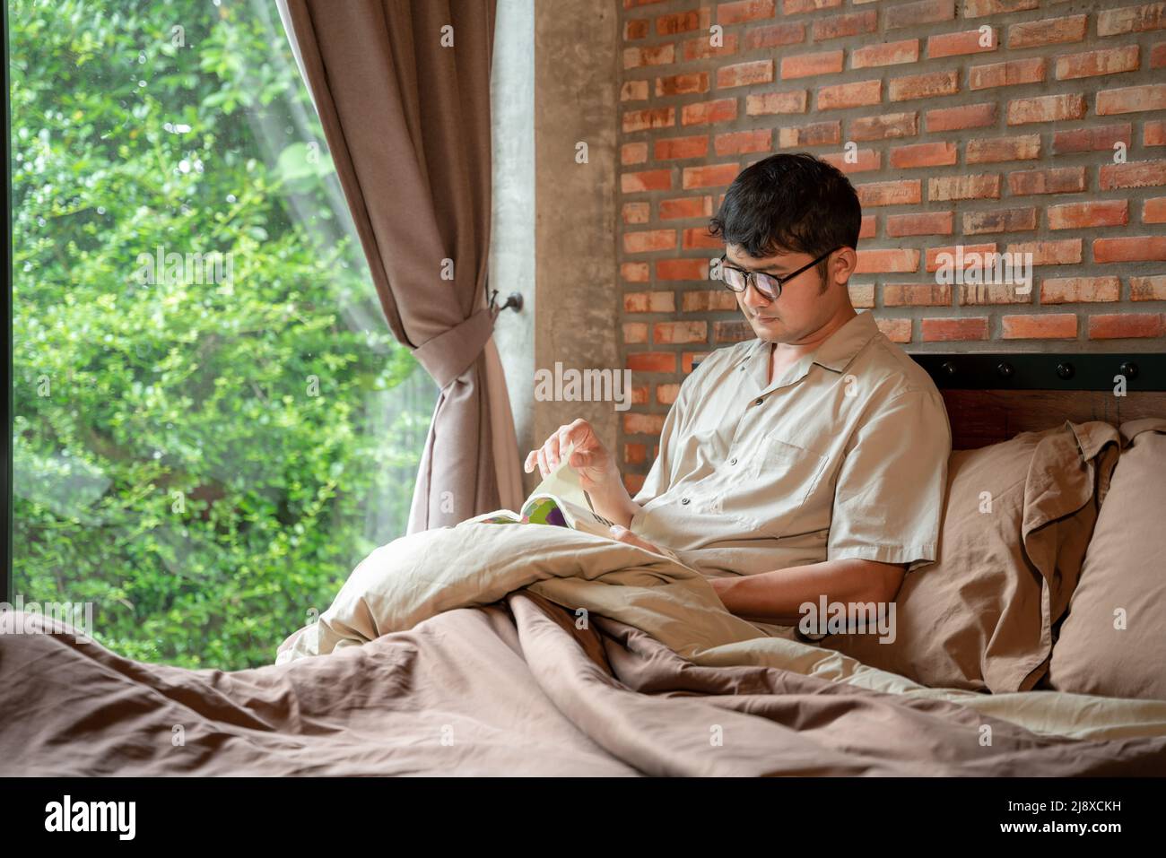Ein Mann, der zu Hause im Schlafzimmer ein Buch liest. Stockfoto