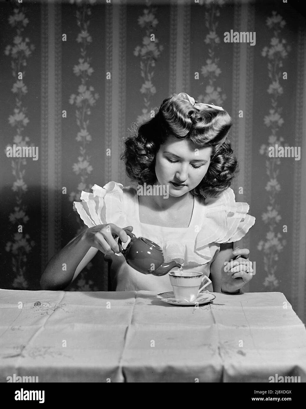Junge Frau gießt Tee in eine Teekannen Ca. 1947 Stockfoto