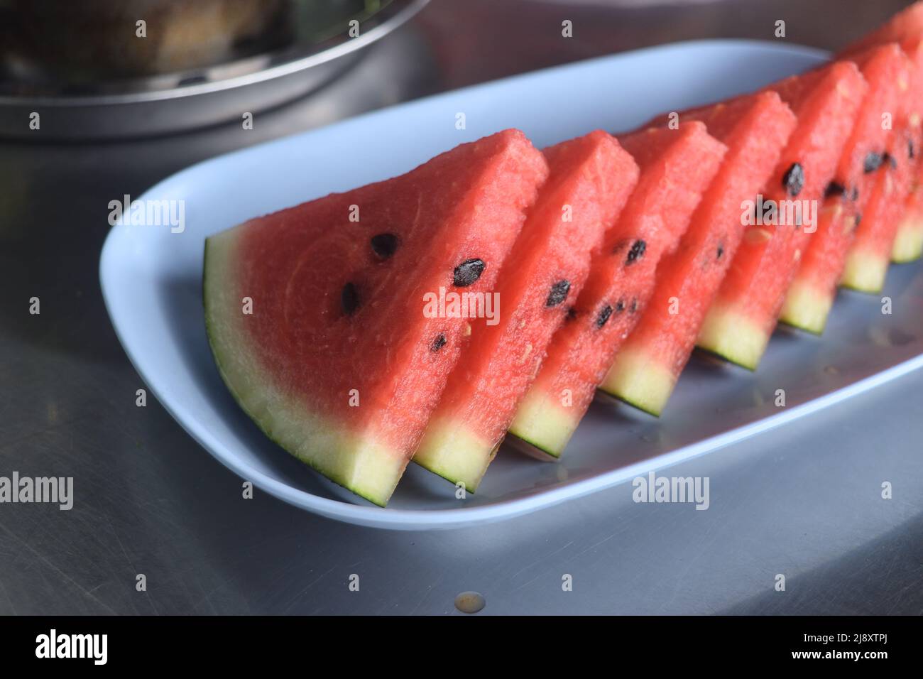 In Scheiben geschnitten von Wassermelone in blauer Schale auf dem Tisch, rote saftige Fruchtfleisch mit grüner Kruste Stockfoto