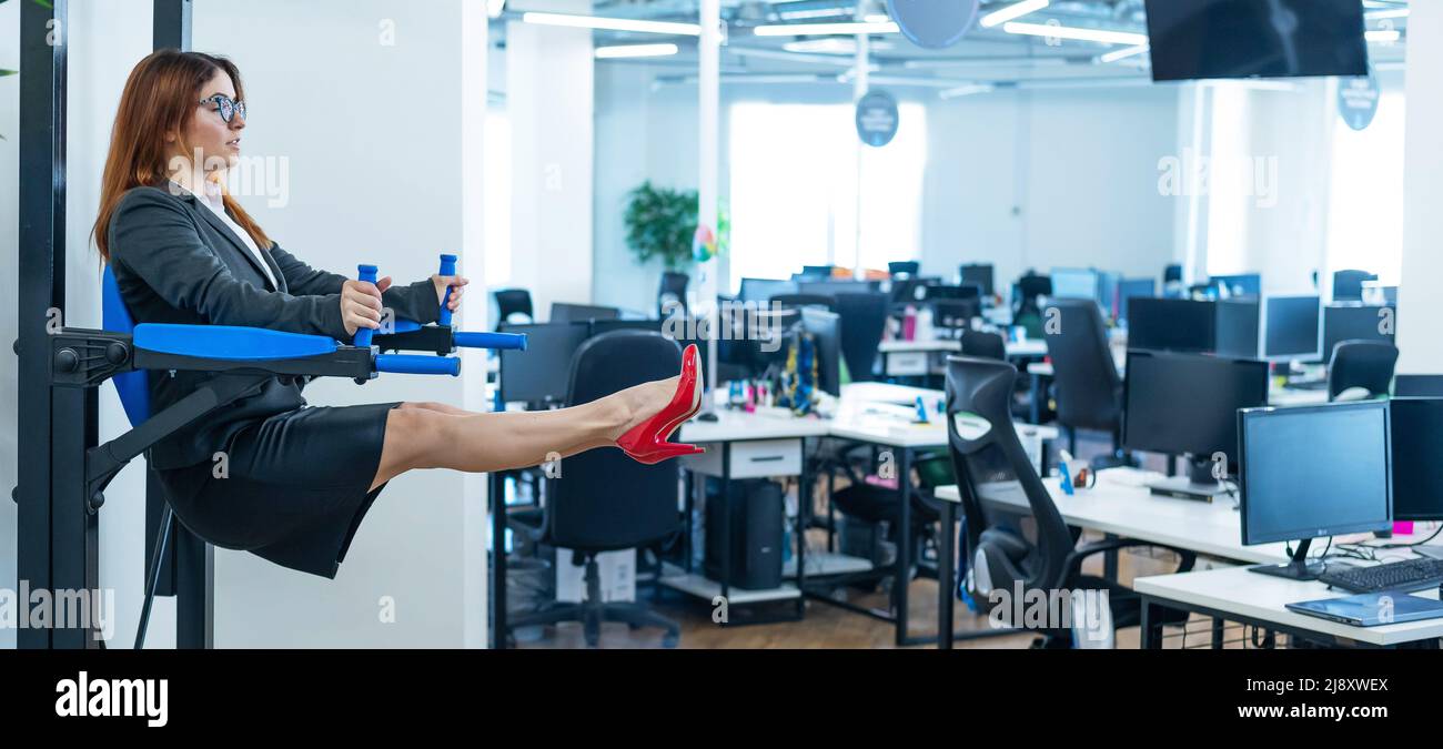 Geschäftsfrau macht Übungen an der montierten horizontalen Bar im Büro. Sport während einer Arbeitspause. Stockfoto