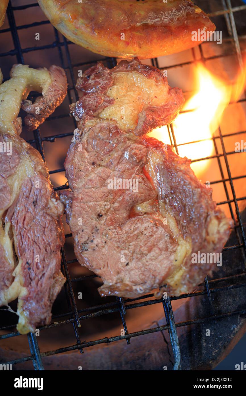Nahaufnahme Grillen des Fleischsteaks auf dem Eisengrill über dem Feuer. Kochen ein Fleisch Grill Stockfoto