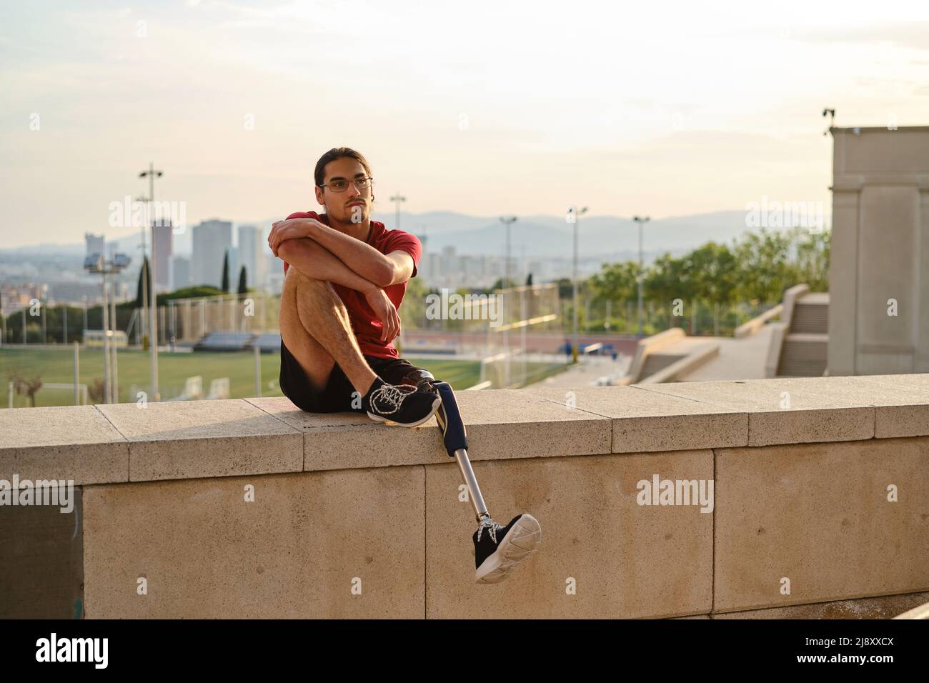 Junger Mann mit einer Behinderung, der sich entspannt, während er im Freien sitzt. Stockfoto