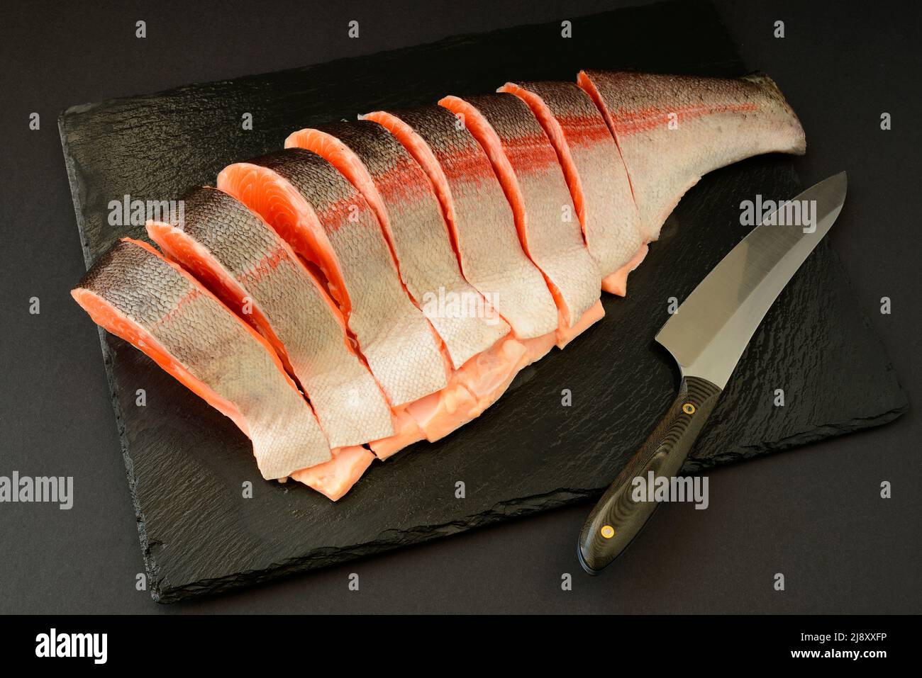 Schneiden und Zubereiten von frischem rohem rotem Fisch, Forelle, Lachs zum Backen oder Braten auf dem Grill, Grill Stockfoto