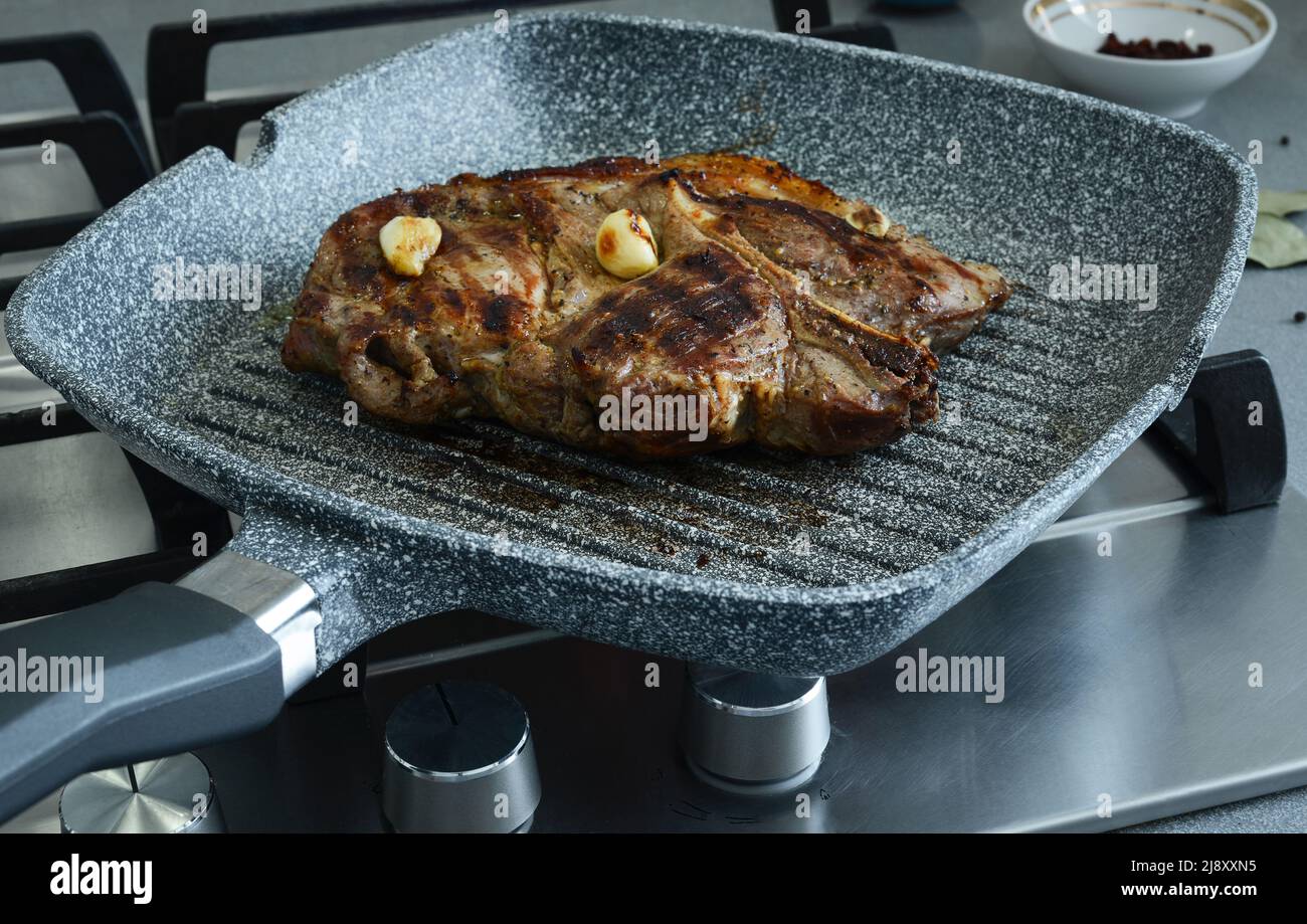 Stück Fleisch mit Knoblauch, in einer gewellten Pfanne gebraten. Braten Fleisch Kochen, gut gemacht Steak Stockfoto