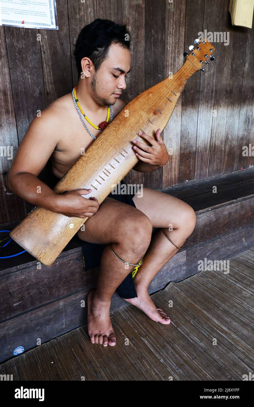 Ein Stammesmann aus Orang Ulu, der das traditionelle Sape spielt, ein traditionelles Saiteninstrument von Borneo. Stockfoto