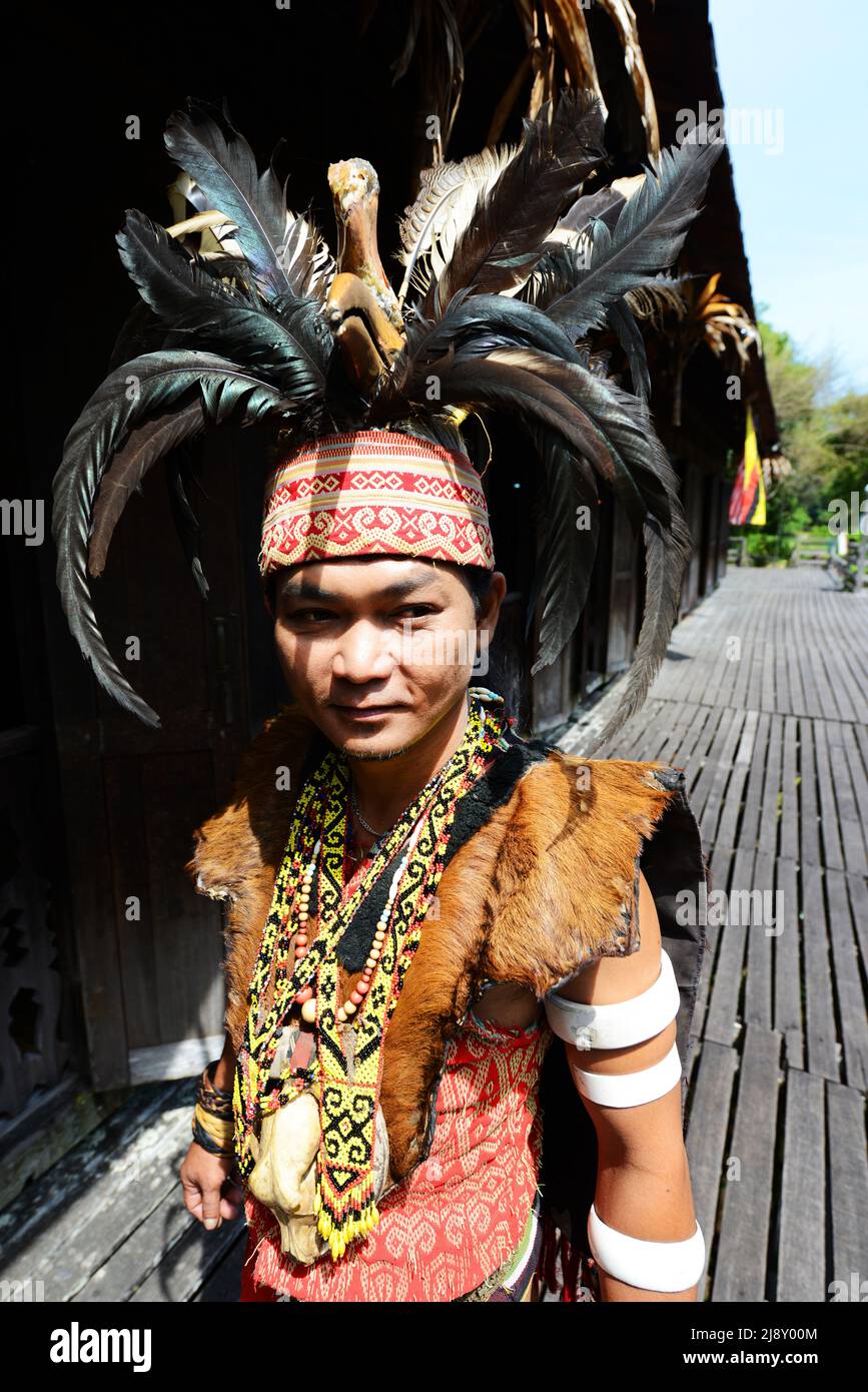 Ein junger IBAN-Mann in Kriegerkopfjäger-Insignien, darunter Hornbillifedern-Kopfschmuck, im Sarawak Cultural Village in der Nähe von Kuching, Sarawak, Malaysia. Stockfoto