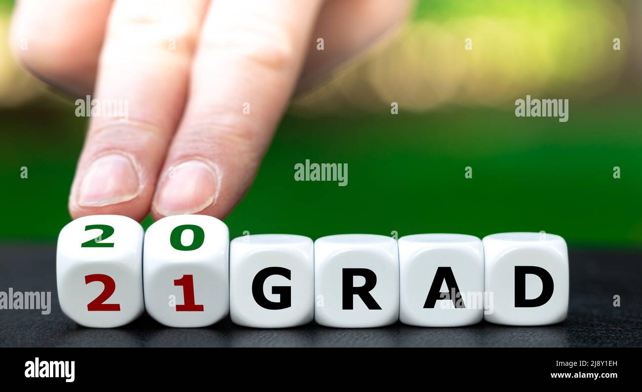 Symbol zur Einsparung von Energiekosten durch Reduzierung der Temperatur. Die Hand dreht Würfel und ändert den Ausdruck „21 Grad“ (21 Grad) in „20 Grad“ (20 Grad). Stockfoto