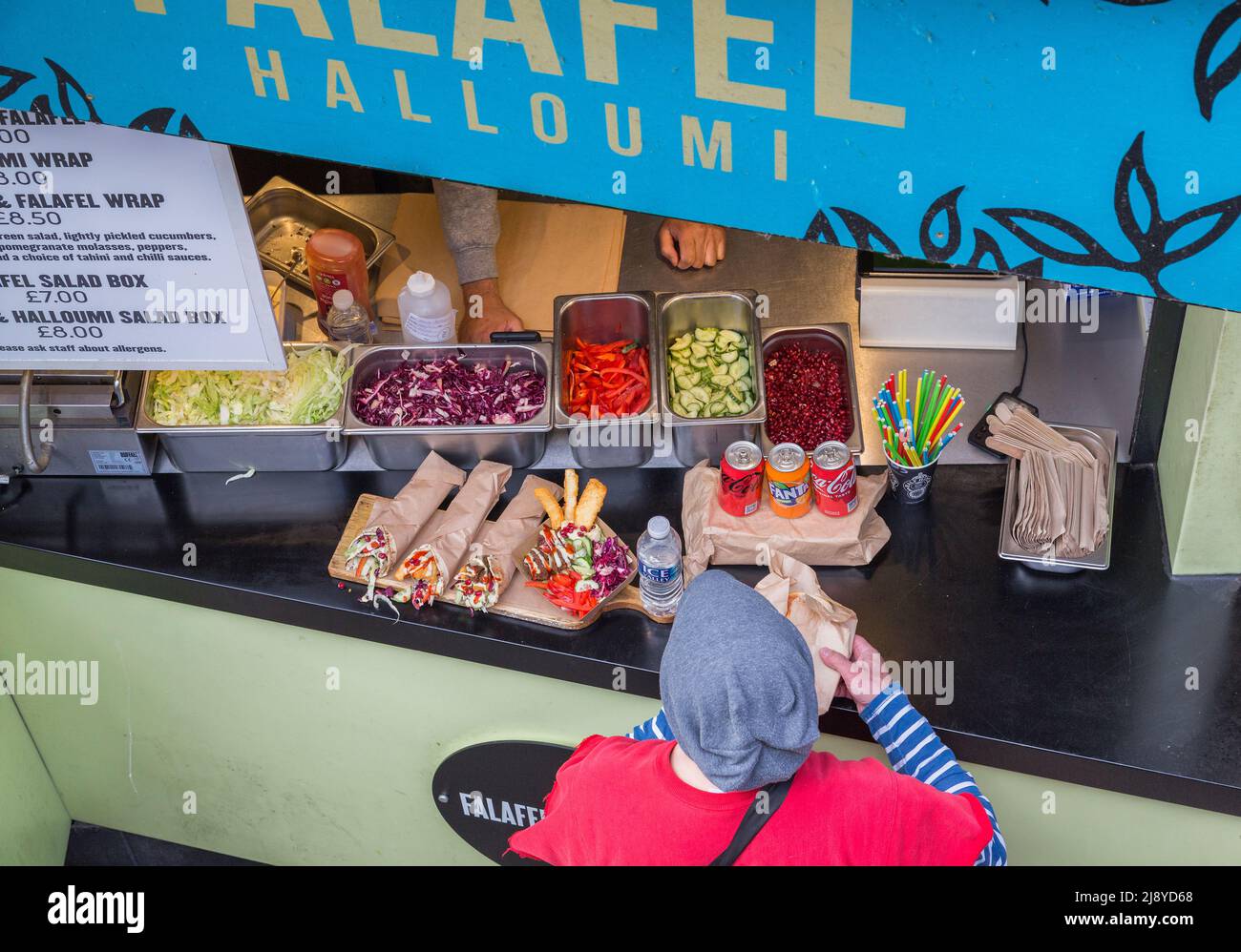 Ein Kunde nimmt seine Bestellung von einem Straßenverkäufer, der Packungen und Salatdosen verkauft, an. Stockfoto