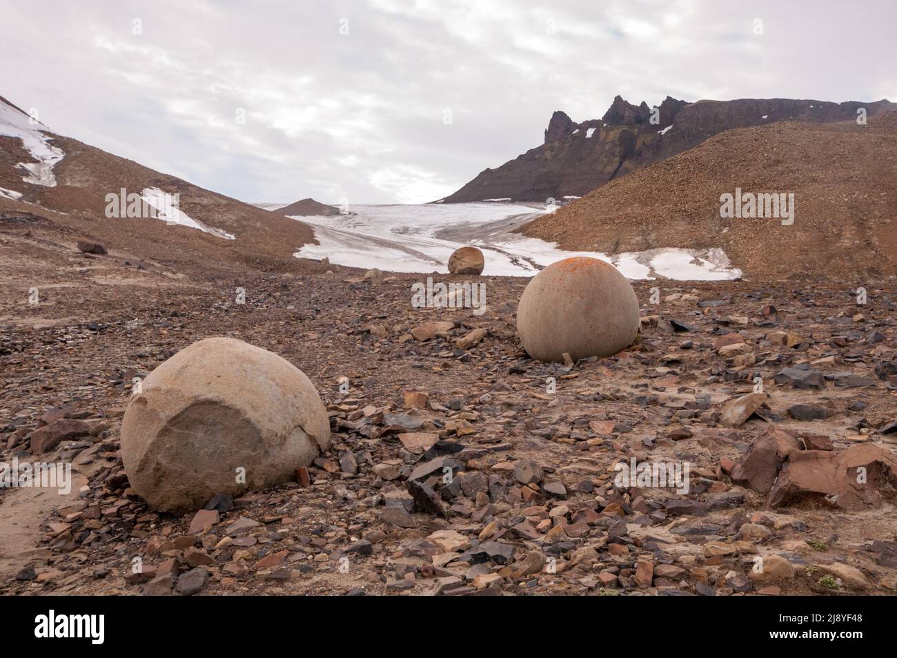 Riesige Felsenbälle unbekannter Herkunft, wahrscheinlich ein Beton, auf Champ Island, Franz Josef Land, Russland, mit Gletscher im Hintergrund Stockfoto