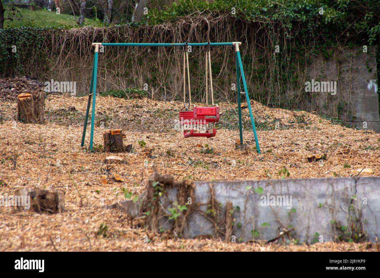 Einsame Schaukel stehlen in einem entwaldeten und verlassenen Garten Stockfoto