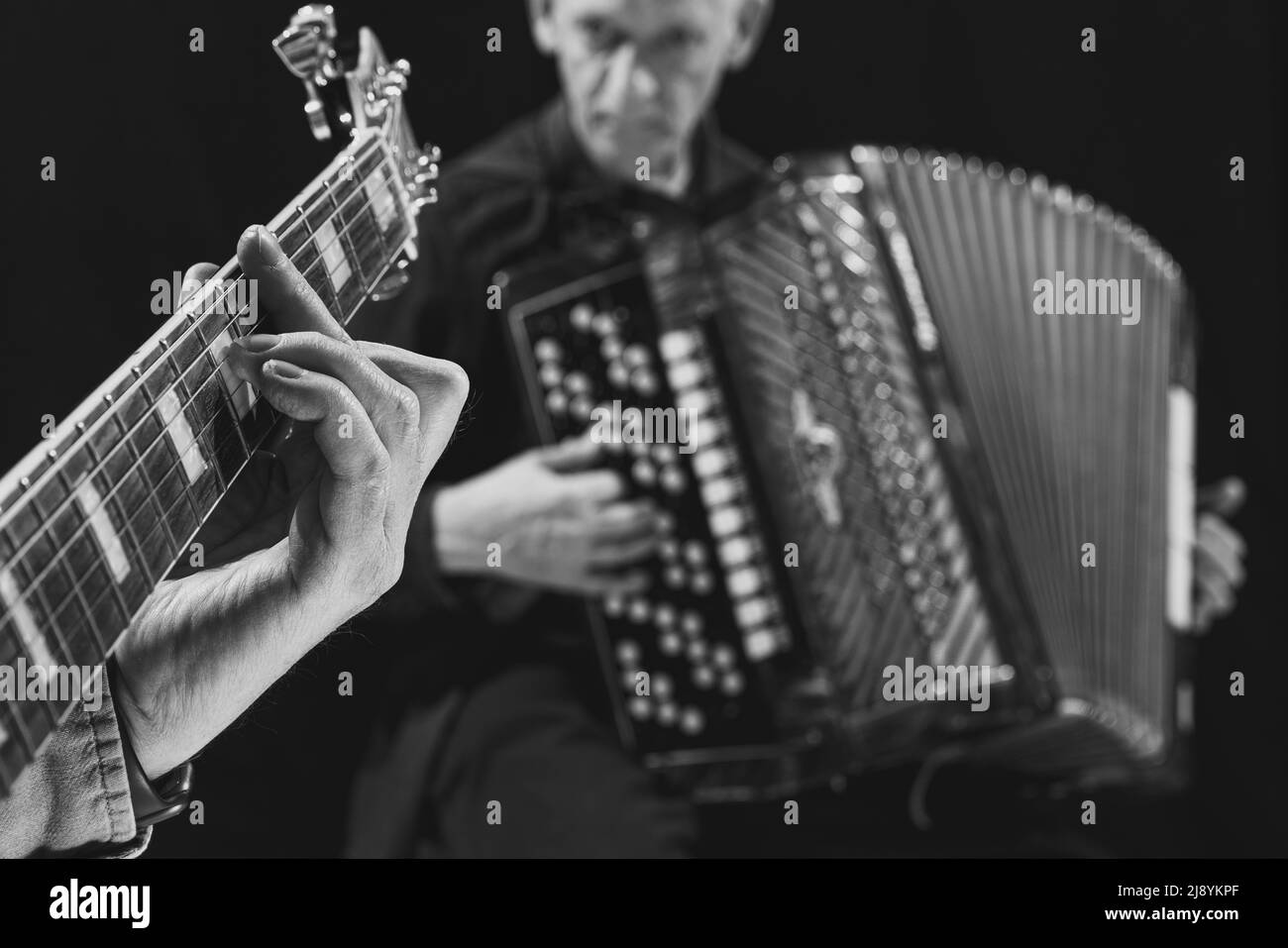 Schwarz-Weiß-Porträt von zwei älteren Männern, Musikern mit Gitarre und Akkordeon im Musikstudio. Konzept von Kunst, Musik, Stil und Kreation. Monochrom Stockfoto