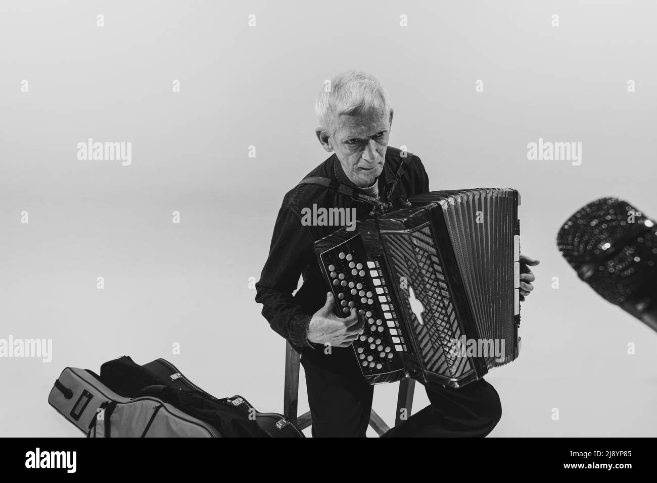 Monochromes Porträt eines senioten Mannes, Retro-Musiker, der die Ziehharmonika auf weißem Hintergrund spielt. Konzept von Kunst, Musik, Stil, ältere Generation Stockfoto
