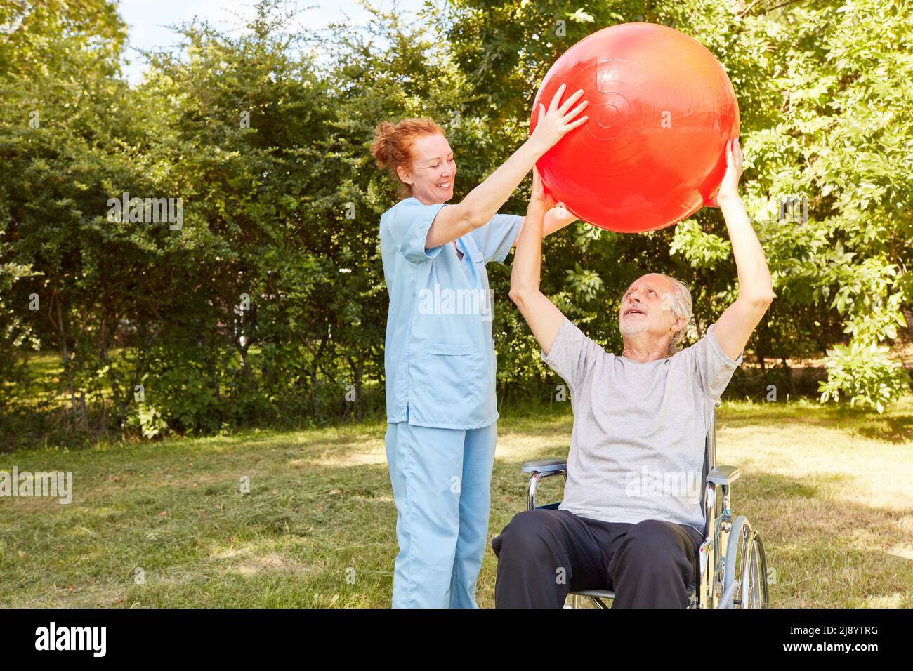 Physiotherapeut und Senior im Rollstuhl trainieren mit Gymnastikball für die Mobilität nach einem Schlaganfall Stockfoto