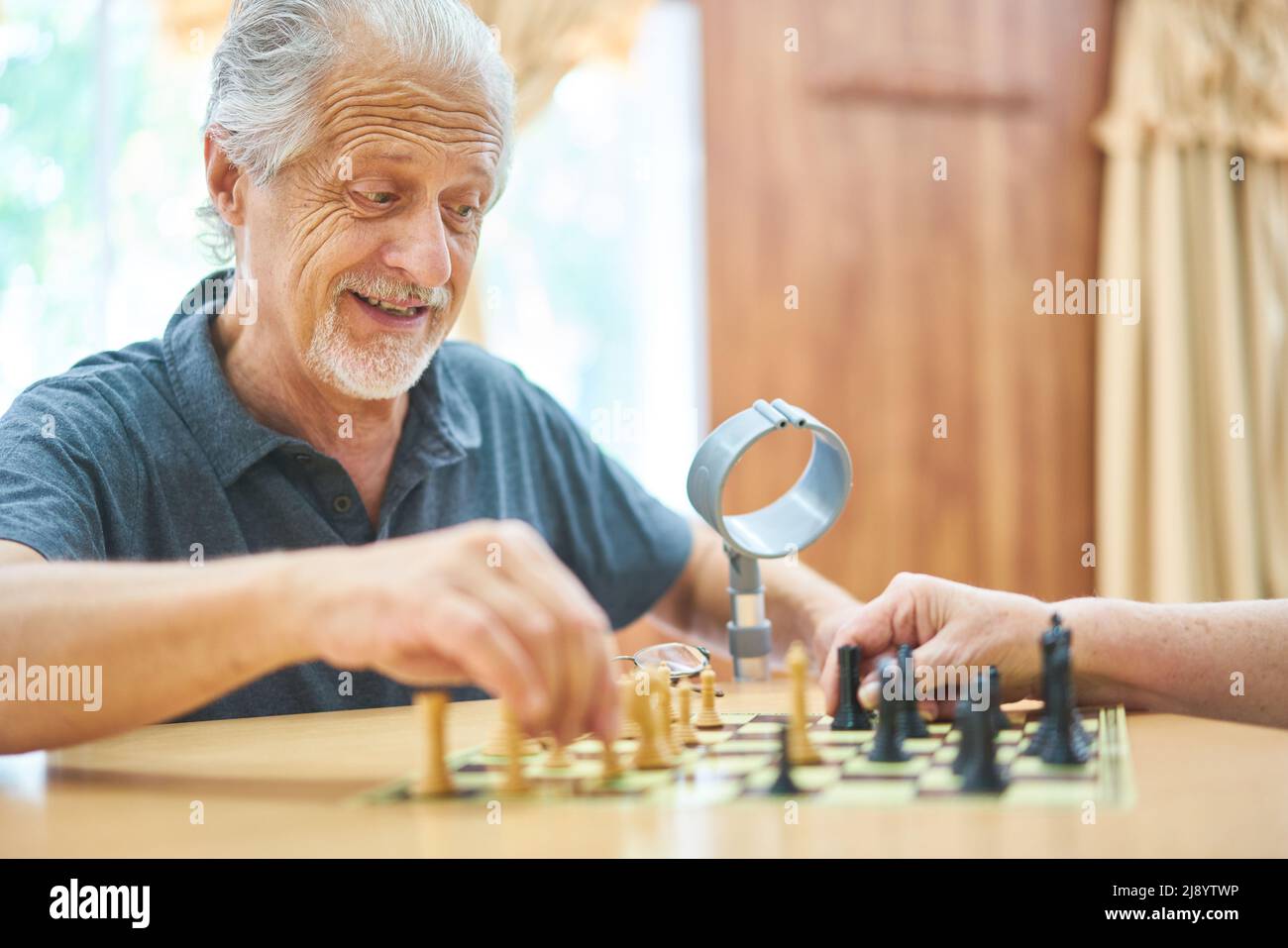 Senior spielt Schach im Altersheim oder zu Hause für Konzentration und Strategie Stockfoto