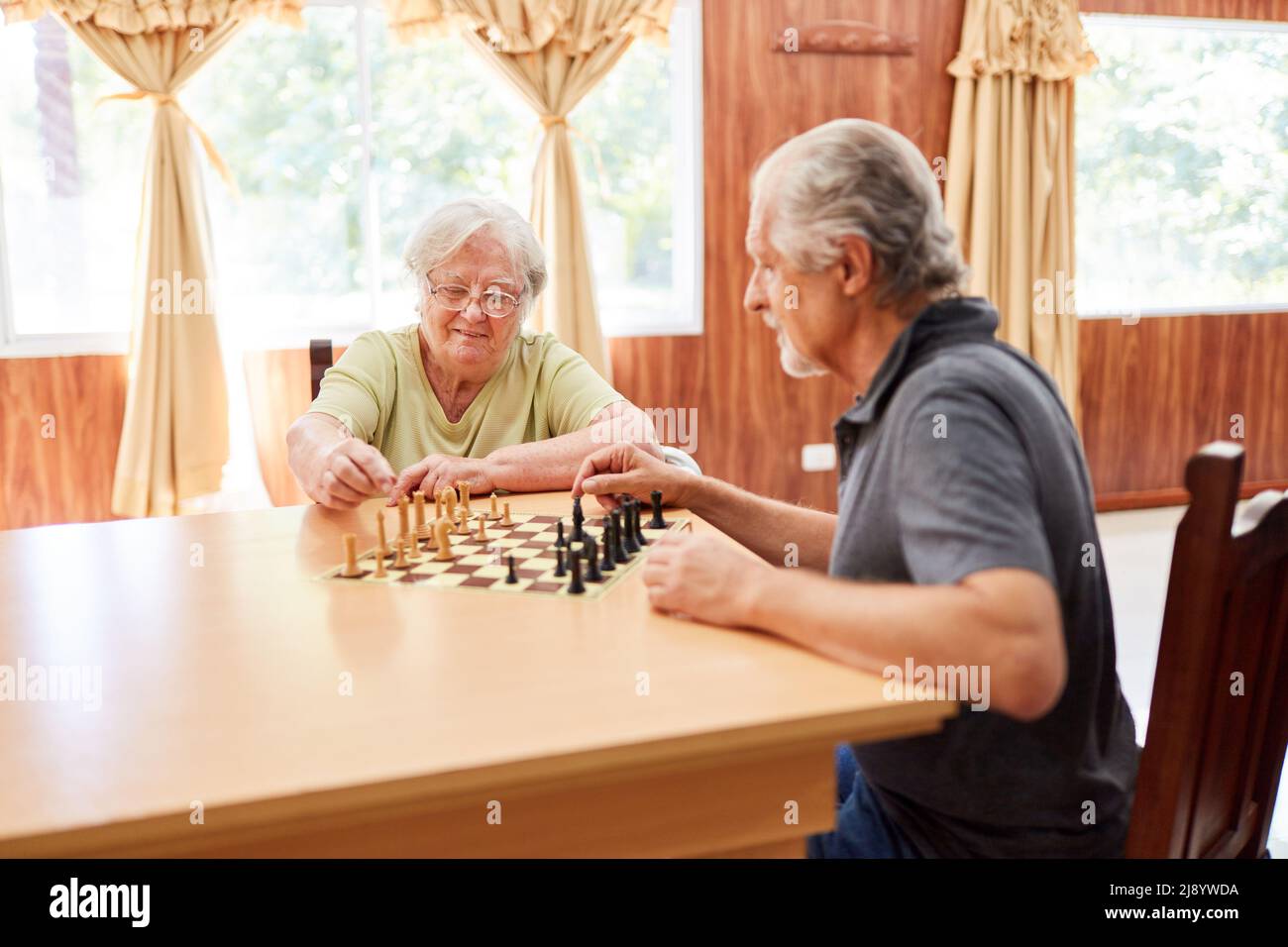 Ein paar Senioren spielen Schach zusammen mit Konzentration als Gedächtnistraining im Pflegeheim Stockfoto