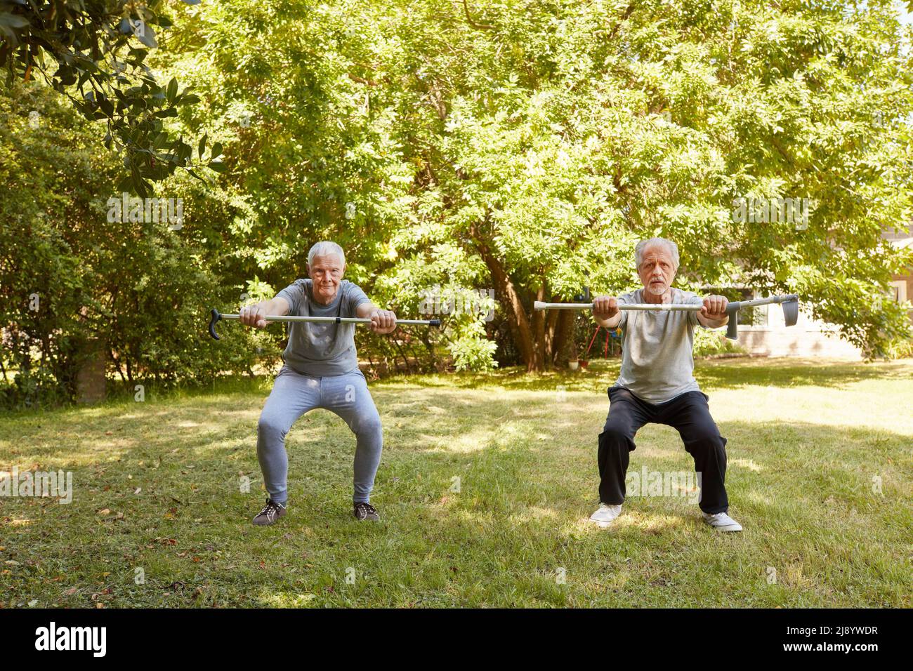 Zwei Senioren mit Krücken hocken im Sommer im Park, um sich als unterhaltsame Reha-Übung zu Vergnügen Stockfoto