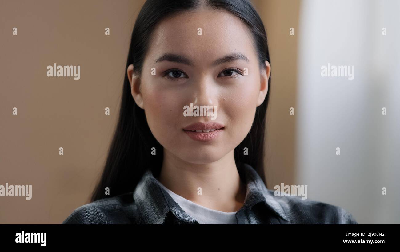 Zuversichtlich 20s Mädchen 30s asiatische ethnische Frau perfekte Haut Gesicht Blick auf Kamera posiert allein zu Hause im Büro tausendjährige koreanische Ethnizität Student profe Stockfoto