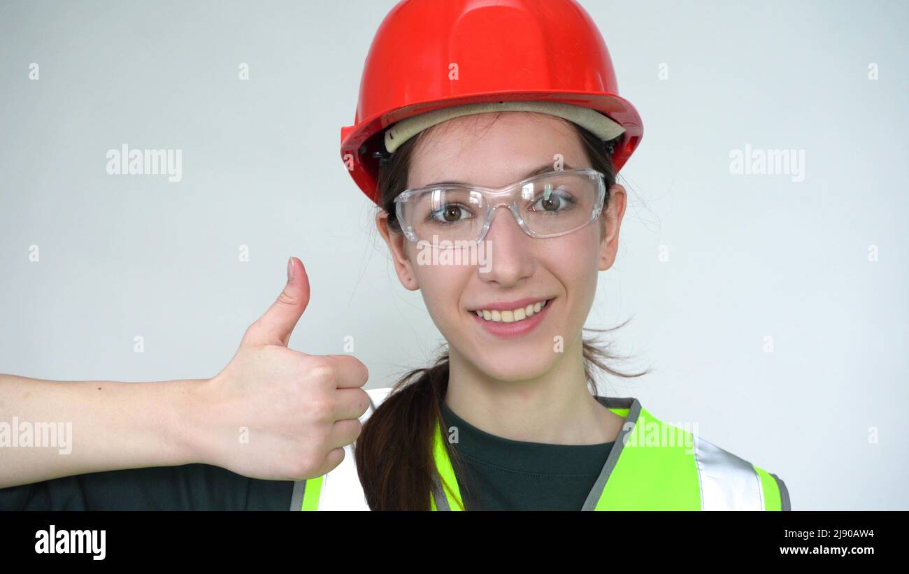 Eine junge, schöne, glückliche Bauarbeiterin zeigt sich begeistert Stockfoto