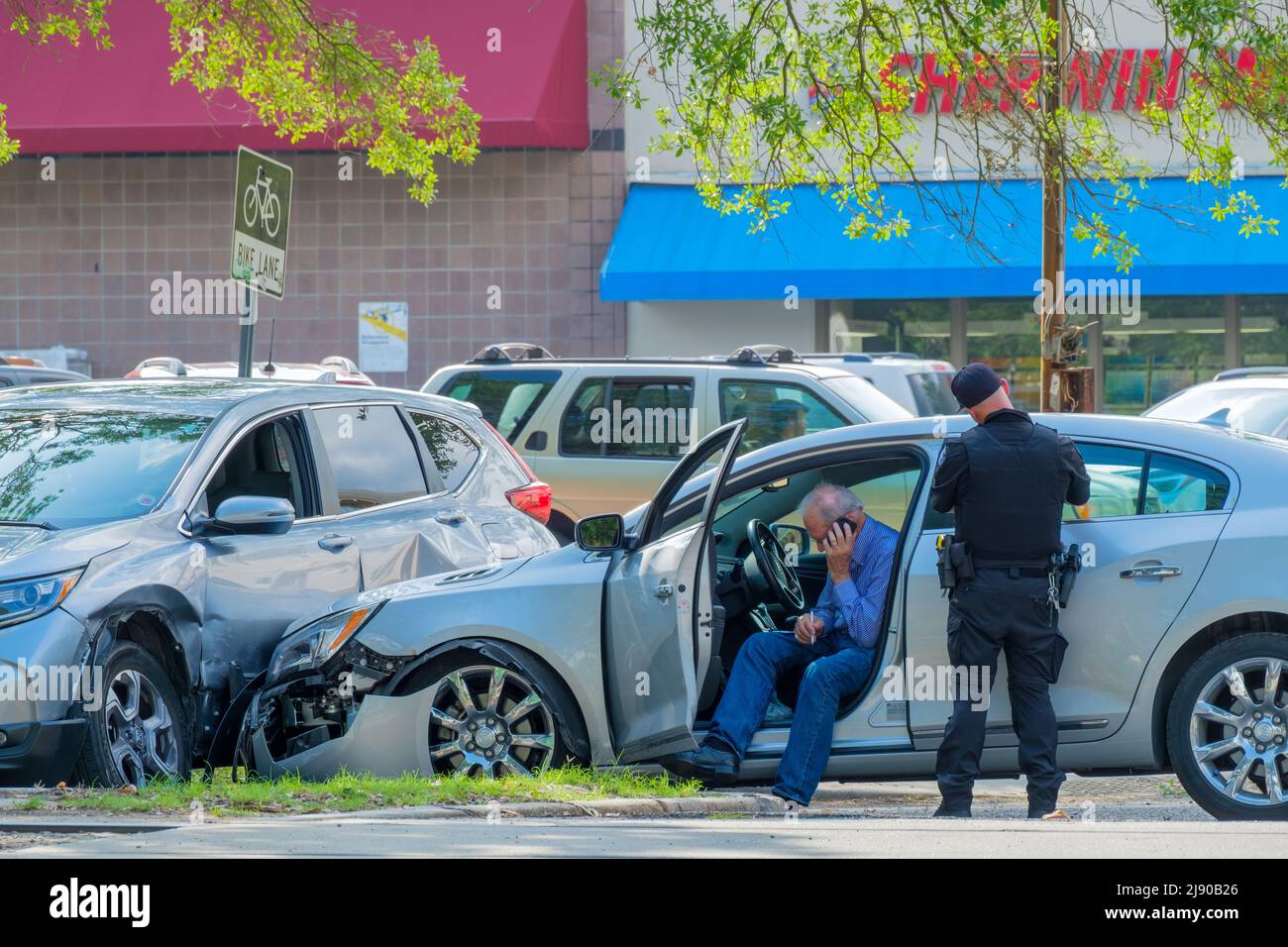 NEW ORLEANS, LA, USA - 9. MAI 2022: Autounfall-Szene mit beschädigten Autos, Polizist schreibt Verkehrsticket und Fahrer (auf Handy) Stockfoto