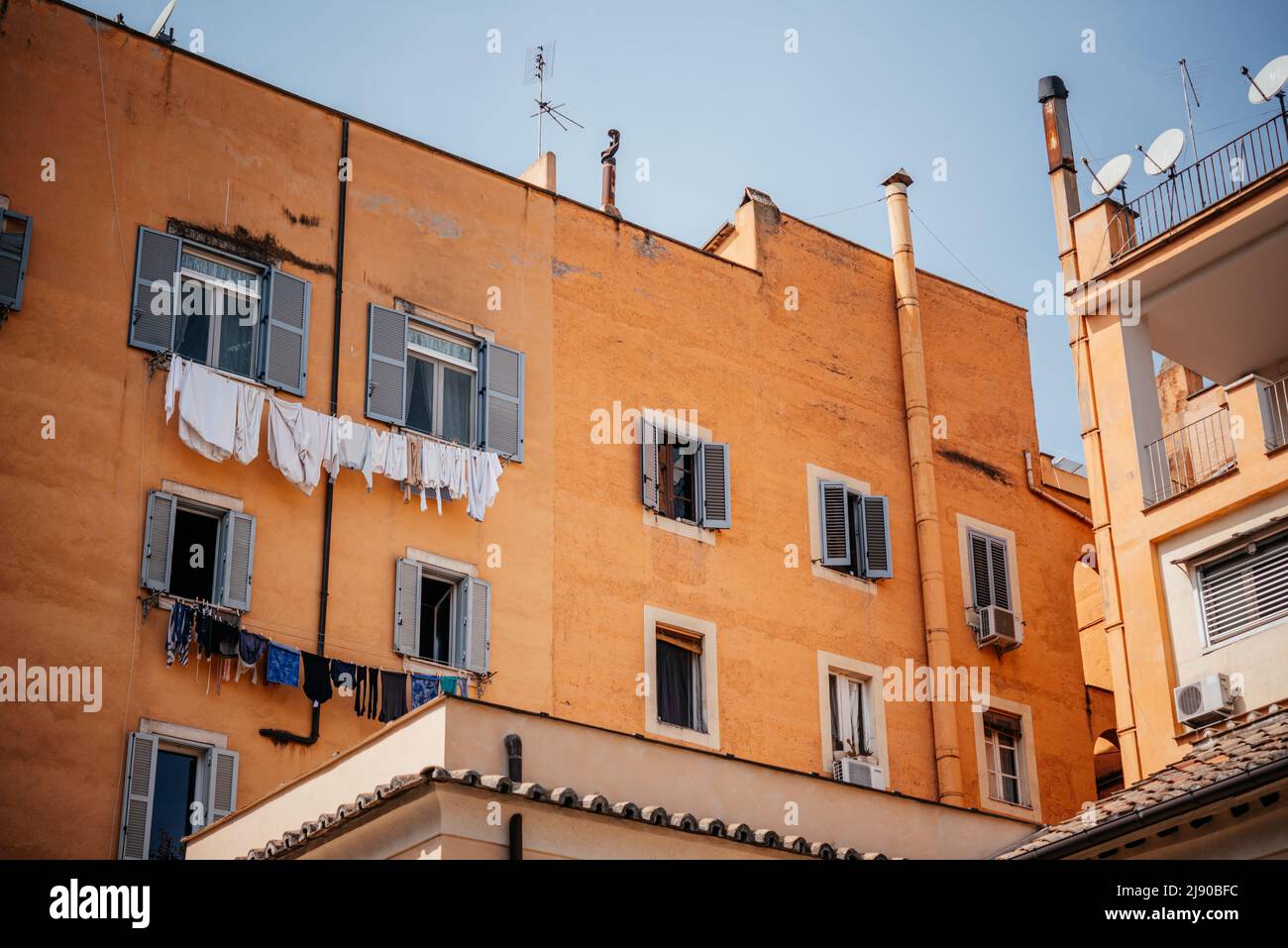 Italienisches Haus mit Fenstern mit Rollläden und Wäschestauken am Seil unter den Fenstern Stockfoto