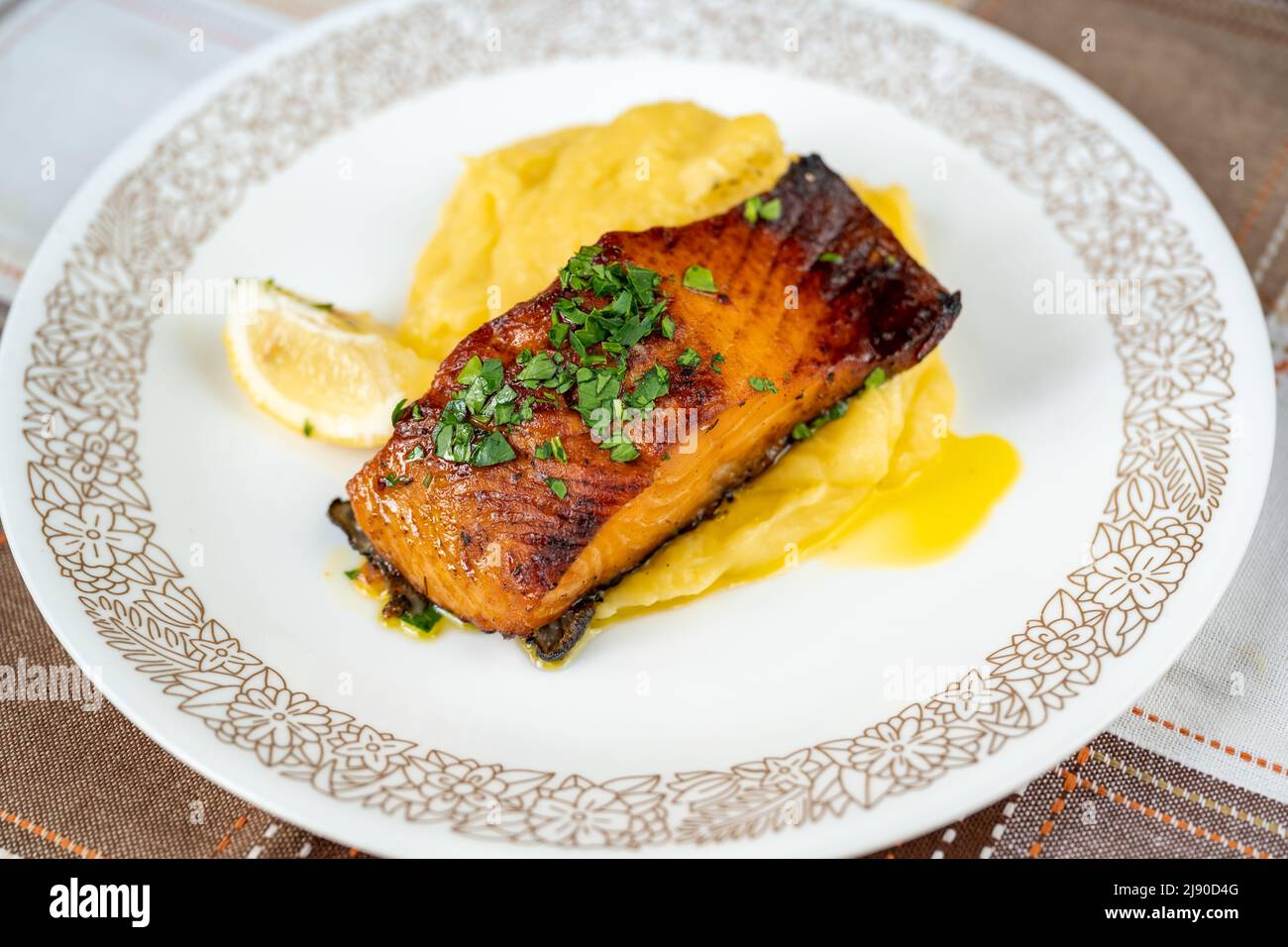 Portion gebratenen Lachs und Kartoffelpüree auf dekorativem weißem Teller, Nahaufnahme. Stockfoto