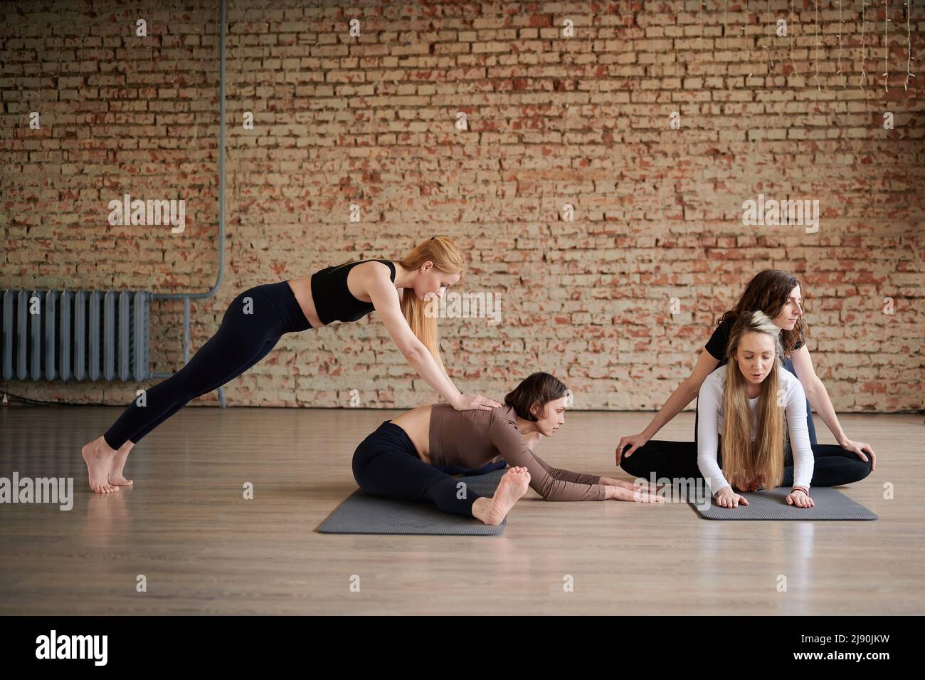 Gruppe von sportlich sportlichen jungen Menschen in Sportbekleidung Stretching im Fitnessstudio und helfen sich gegenseitig, Gruppe Fitness-Konzept Stockfoto