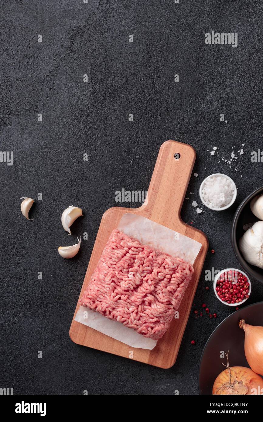 Rohes Hackfleisch, Farce Fleischportion auf einem Holzbrett auf schwarzem Hintergrund Stockfoto