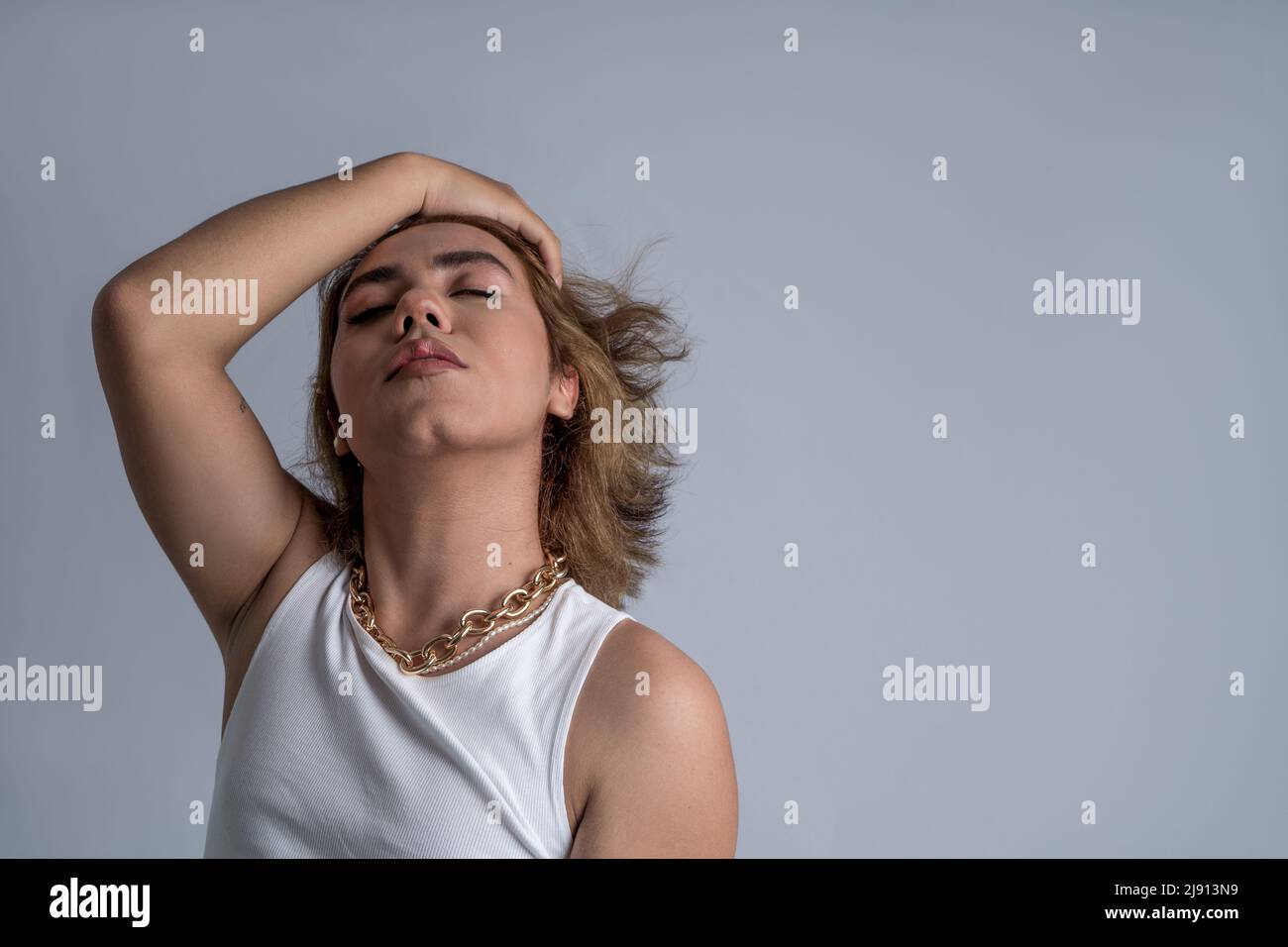 Portrait von angrogynen jungen Akkpetanz mit langen Haaren und coolem Stil mit ruhiger Haltung im Studio Stockfoto