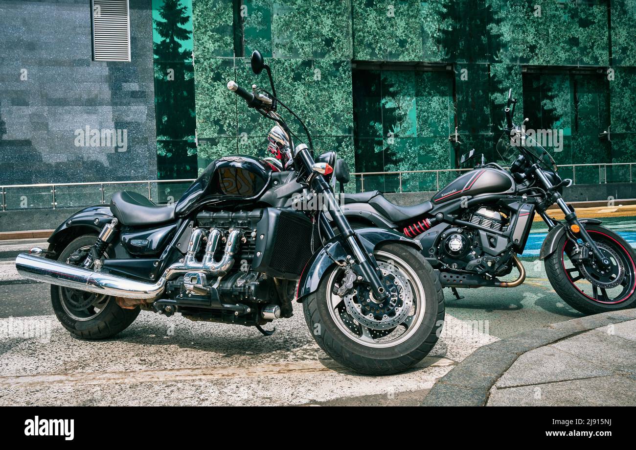 Stilvolle Triumph- und Kawasaki-Motorräder auf dem Parkplatz in der Nähe des Bürogebäudes in Moskau-Stadt: Moskau, Russland - 11. Mai 2022 Stockfoto