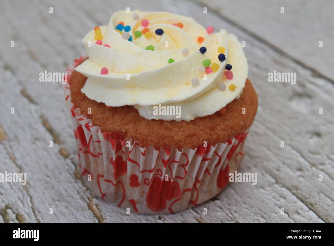 Süßer Kuchen mit tutti frutti bestreut oben auf dem Holztisch weißen Hintergrund. Stockfoto