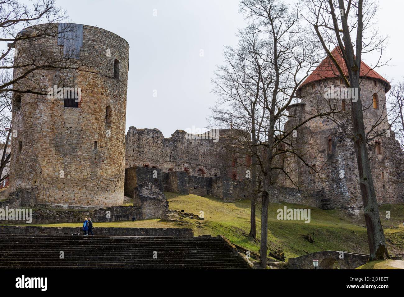 Ein Paar, das an den Ruinen und breiten Steintreppen der mittelalterlichen Burg in Cesis, Lettland, vorbei geht. Stockfoto