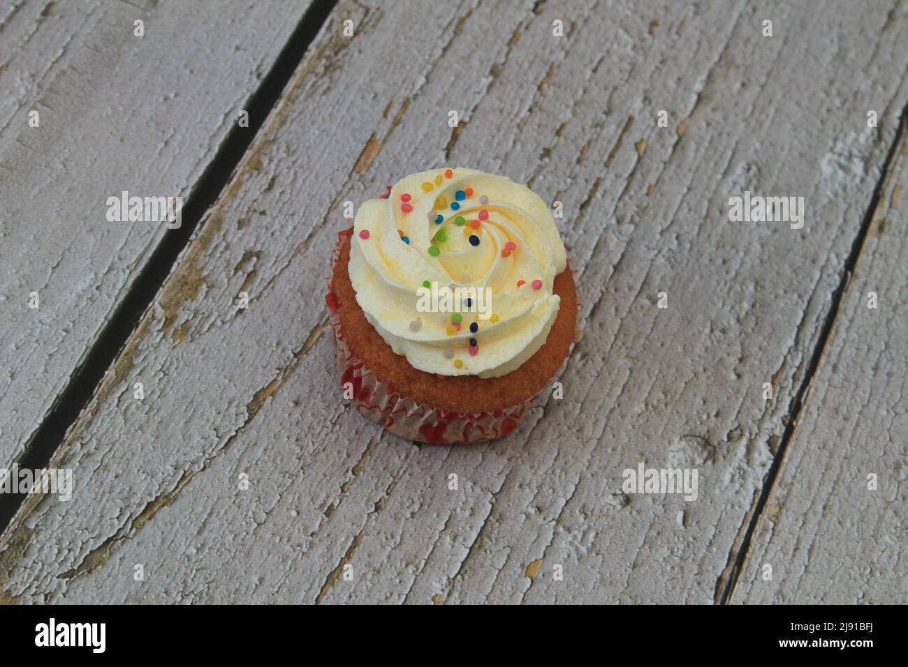 Süßer Kuchen mit tutti frutti bestreut oben auf dem Holztisch weißen Hintergrund. Stockfoto